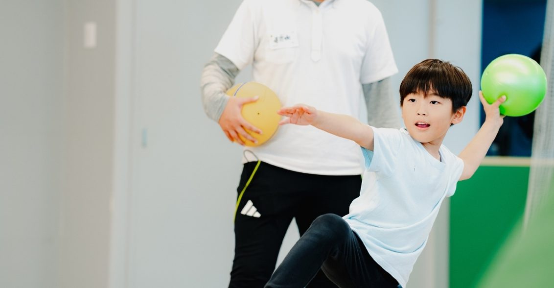 ボールを投げる子どもとコーチ